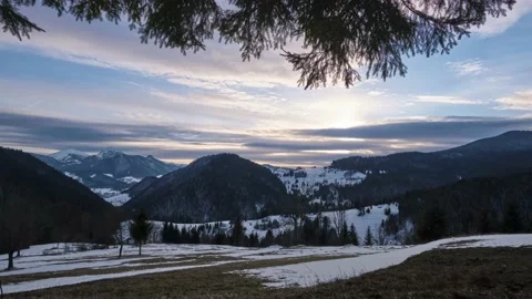 A mountainous and hilly landscape between winter and autumn. The setting sun 動画素材 236249945