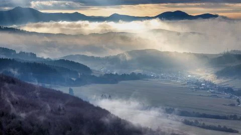 Mountainous landscape with misty valleys at dramatic light. Stock Photos