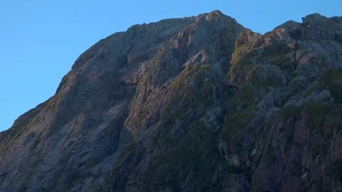 Mountains and cliffs in the sun with green trees in New Zealand Milford Sound Stock Footage 132062946