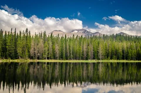 Mountains and forest reflected in a lake. Stock Photos