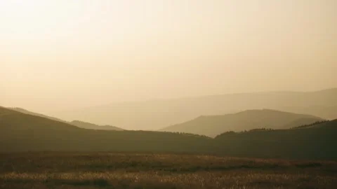 Mountains and hills in the distance during a hazy afternoon with soft light and  Stock Footage 343843095