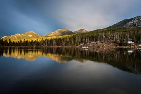 Mountains and trees reflected in a calm lake. Stock Photos