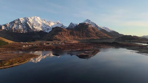 Mountains and water reflect during sunset in a landscape with snow capped peaks Stock Footage 334773913