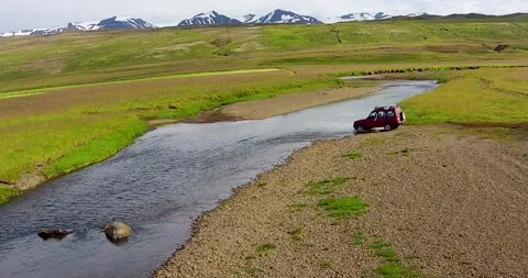 With mountains in the background, an SUV crosses a river Video stock 234818843