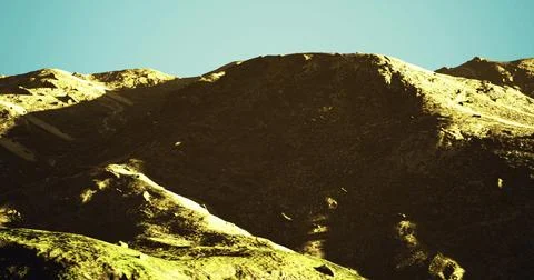 Mountains basking in sunlight under a clear sky during midday hours Stock Illustration