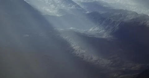 Mountains bathed in soft light with dramatic shadows at sunrise Stock Illustration