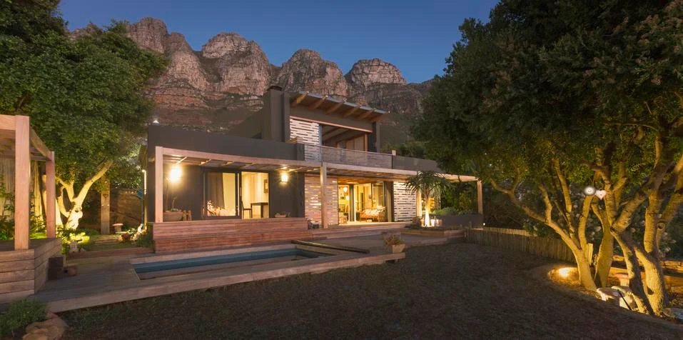 Mountains behind illuminated modern, luxury home showcase exterior house at Stock Photos