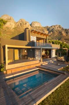Mountains behind sunny luxury home showcase exterior house with swimming pool Stock Photos