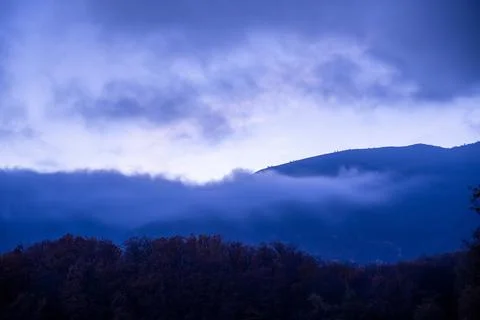 Mountains in the clouds against the blue twilight sky Stock Photos