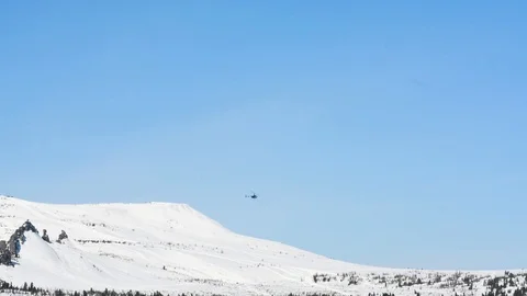 Mountains covered with snow over which a rescue helicopter flies on a Sunny day Stock Footage 106197331
