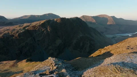 Mountains at dawn with flight over cliff edge revealing dark valley and Vidéo 256967726