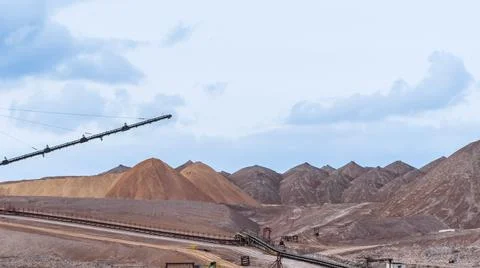 Mountains of empty ore when mining potassium on cloudy sky background. Transp Foto stock