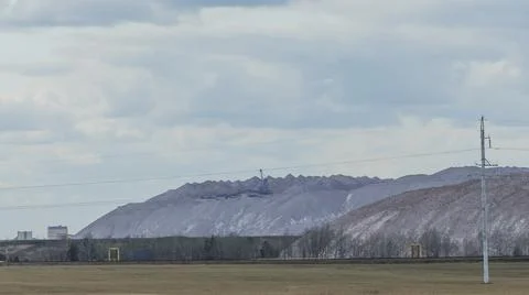Mountains of empty ore when mining potassium on cloudy sky background. Transp Stock-Fotos