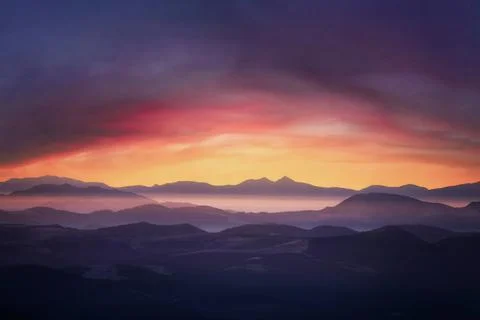 Mountains in fog at dramatic sunset. Stock Photos