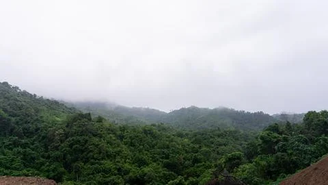 Mountains with greenery partially covered by clouds Stock Photos