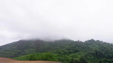 Mountains with greenery partially covered by clouds Stock Photos