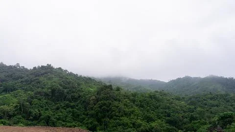 Mountains with greenery partially covered by clouds Stock Photos