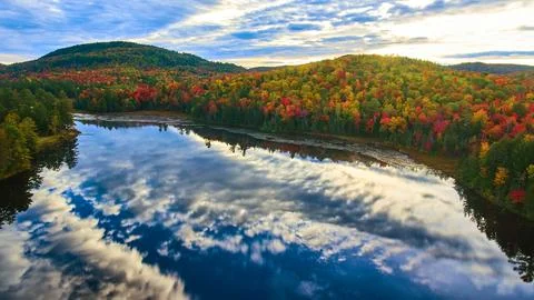 Mountains in peak fall surround reflective lake in early morning light Stock Photos