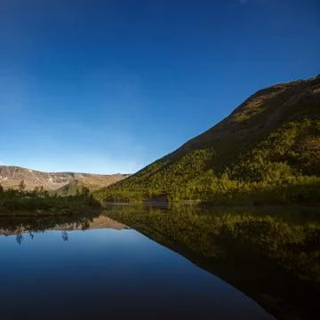 Mountains reflected in the smooth surface of the lake at dawn. Stock Photos