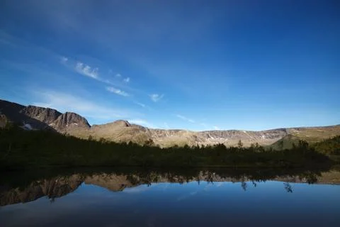 Mountains reflected in the smooth surface of the lake at dawn. Stock Photos