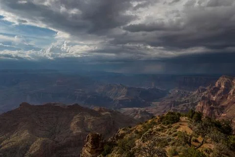 Mountains sit below some dark clouds above them as the sun sets Stock Photos