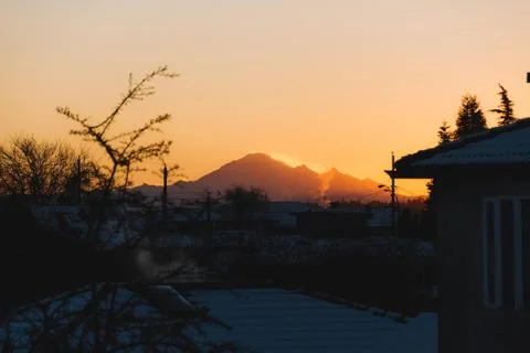 Mountains in snow with building in front while sunset or sunrise Stock Photos