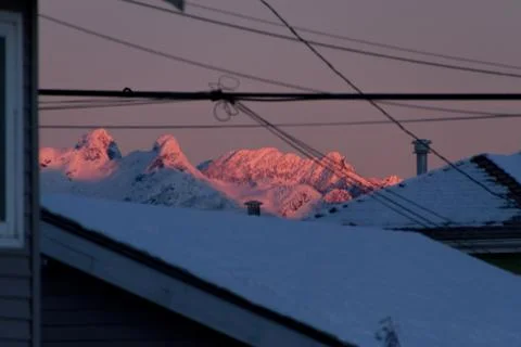 Mountains in snow with building in front while sunset or sunrise Stock Photos