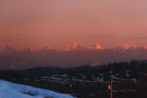 Mountains in snow with building in front while sunset or sunrise Stock Photos