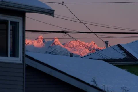 Mountains in snow with building in front while sunset or sunrise Stock Photos