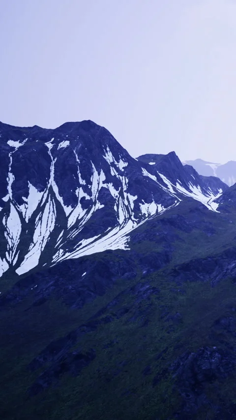 Mountains stand tall under a clear sky with patches of snow at dusk Stock Footage 334259510