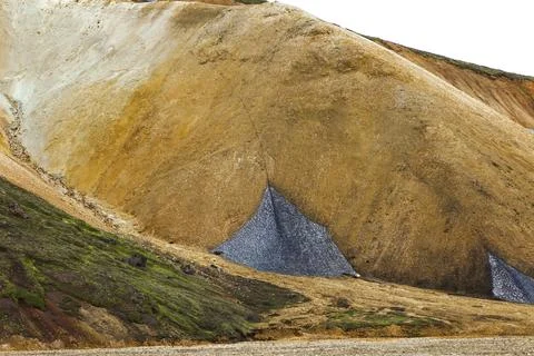 Mountainside with triangular shaped patches of grayish snow in Landmannalaugar, Stockfoto's
