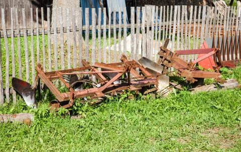 Mounted plow from the tractor lying on the grass in the countryside Stock Photos