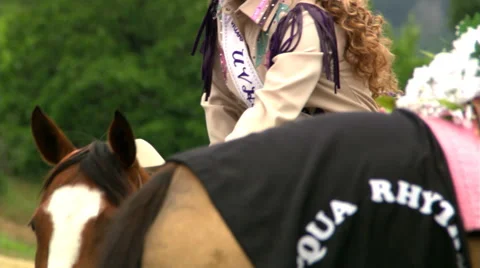 Mounted rodeo queen viewed from across a flower-decked saddle in foreground Stock Footage 59533286