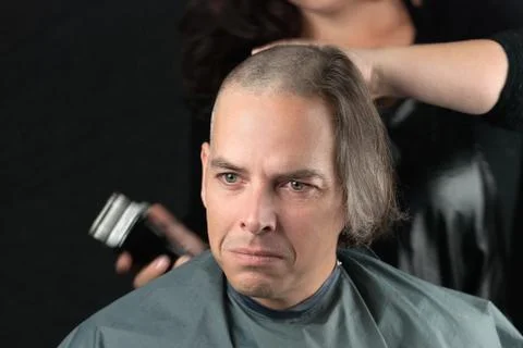 Mourning man getting long hair shaved off for cancer fundraiser Stock Photos