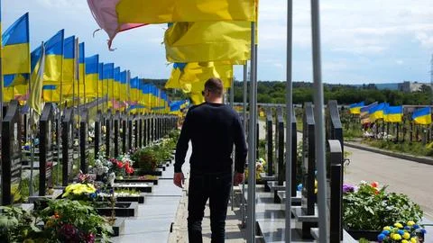 Mourning man go among countless graves of ukrainian soldiers with national fl 写真素材