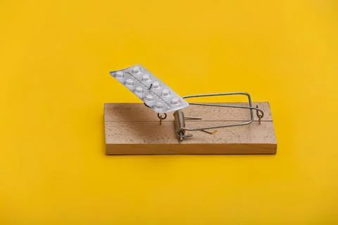 Mouse trap with pills on a yellow background Fotos Stock