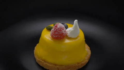 Mousse dessert covered with yellow glaze rotating on black plate Stock Footage 99251569