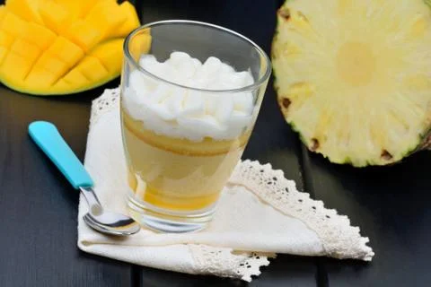 Mousse of mango fruit and pineapple in a glass jar on black table Stock Photos