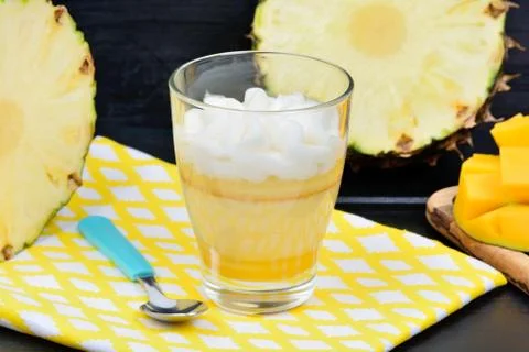 Mousse of pineapple fruit and mango in a glass jar on table Foto stock