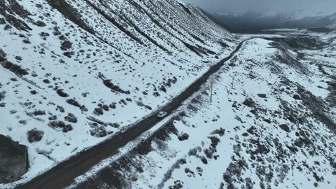 [MOV] Tracking a White Car on a Snow Dusted Valley Road Vídeo Stock 344717191