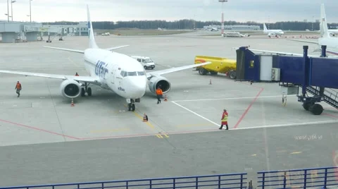 Movable jet bridge move to arrived airliner, ground personnel work at airport Stock Footage 62400326