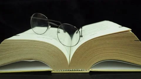 Move the camera slowly from left to right.glasses and books on the table Stock-Footage 182473036
