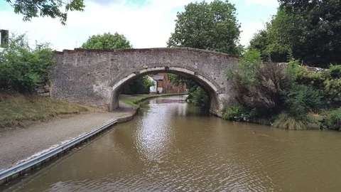 Move forward under canal bridge, behind tree reveals brick house Stock Footage 93074512