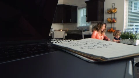 Move past laptop and notepad to reveal mother and sons in kitchen RED camera Stockbeeldmateriaal 122561411