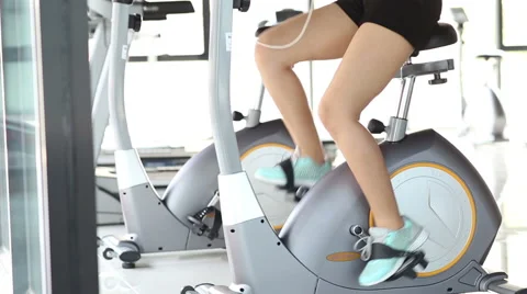 Move up of young smiling woman using a exercise bike at the gym Stock Footage 60364204