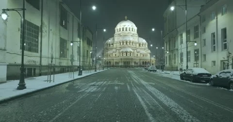 Movement between snowy buildings and an Orthodox church in nighttime Sofia Stock Footage 297782592