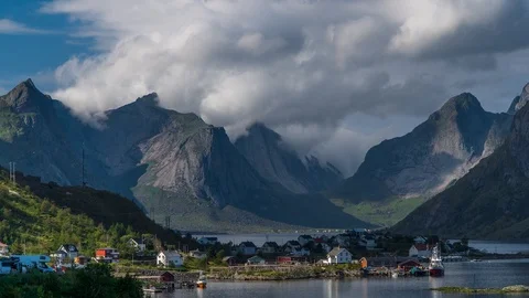 The movement of clouds over beautiful mountain peaks and a small fishing village Stock Footage 95566967