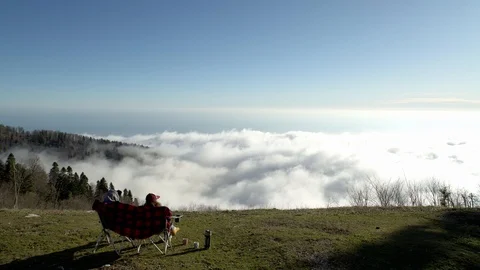Movement of clouds on the surface of the mountain. The couple sits watching Stock Footage 126995456