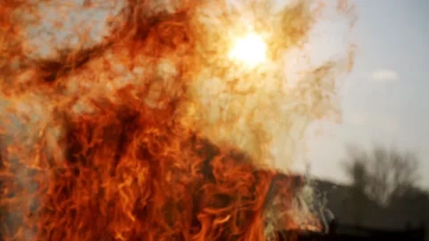 Movement of the flame of a large fire against the background of the sun Stock Footage 89415812