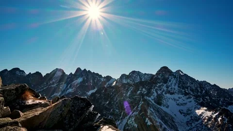 Movement of the sun in the blue sky over the alpine mountains.Mountain nature in Video stock 236029512